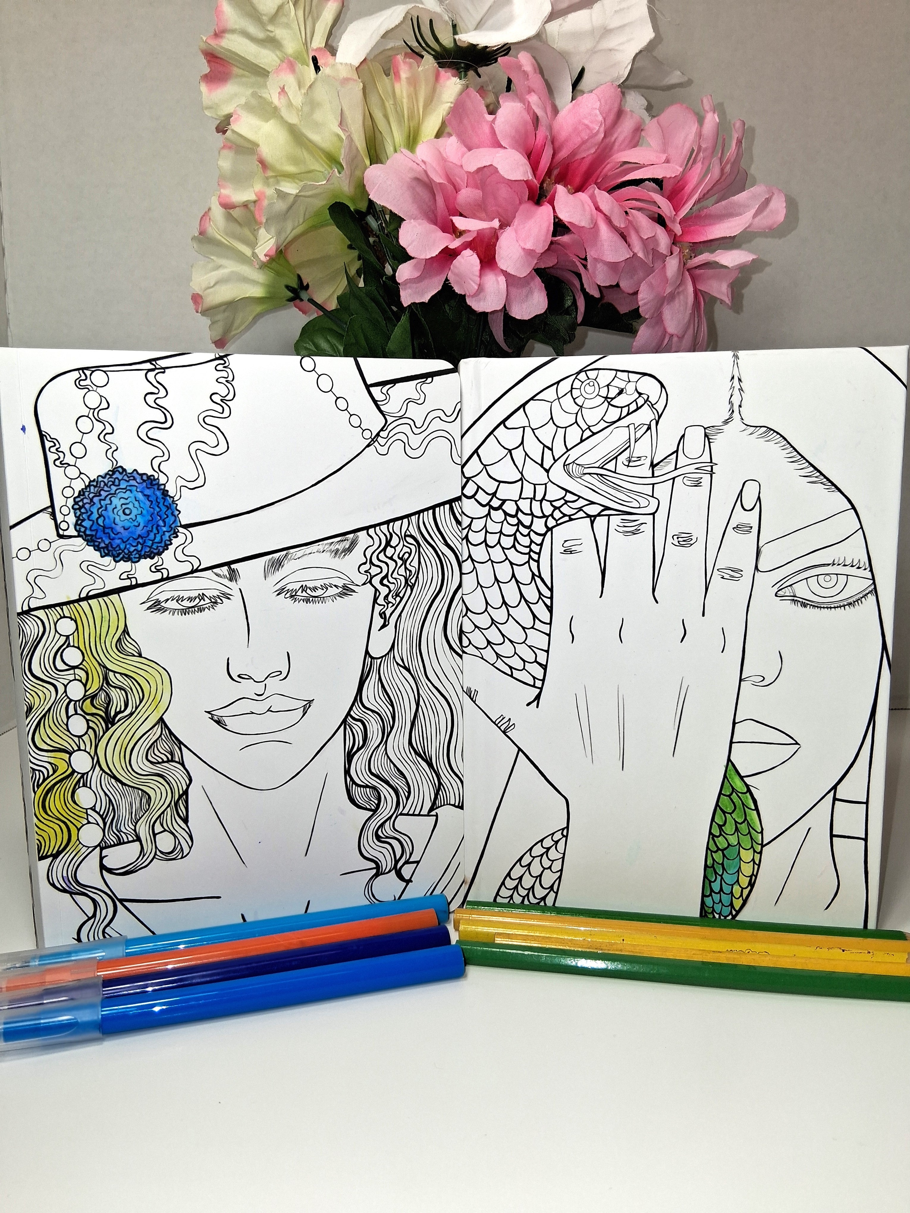 Coloring book with artistic illustrations, markers, and flowers on a table. Two different books. Softcover journal and the other is hardcover notebook. You can color the front on book. Anime-ish inspired.
