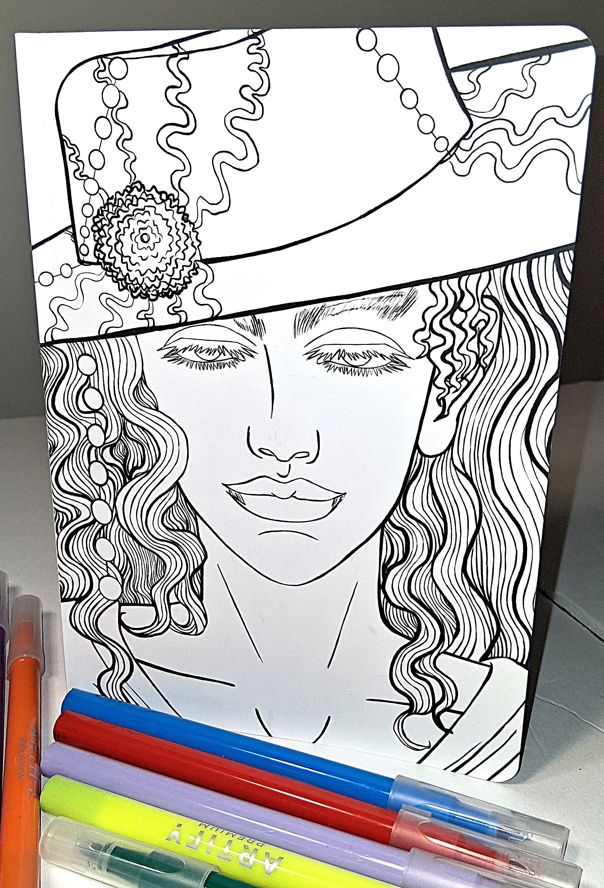 Coloring book with a design of a woman's face and decorative elements, accompanied by markers.